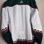 Brand New  Size: 60G   100% polyester  Officially licensed by the NHL  Made by Adidas  Relaxed Fit  Crewneck  Arizona Coyotes Crest  White/Green/Black/Burgundy   Steal at this price!  No refund if tag is removed